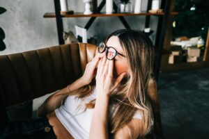 Young woman rubs her eyes after using glasses. Eye pain or fatigue concept.